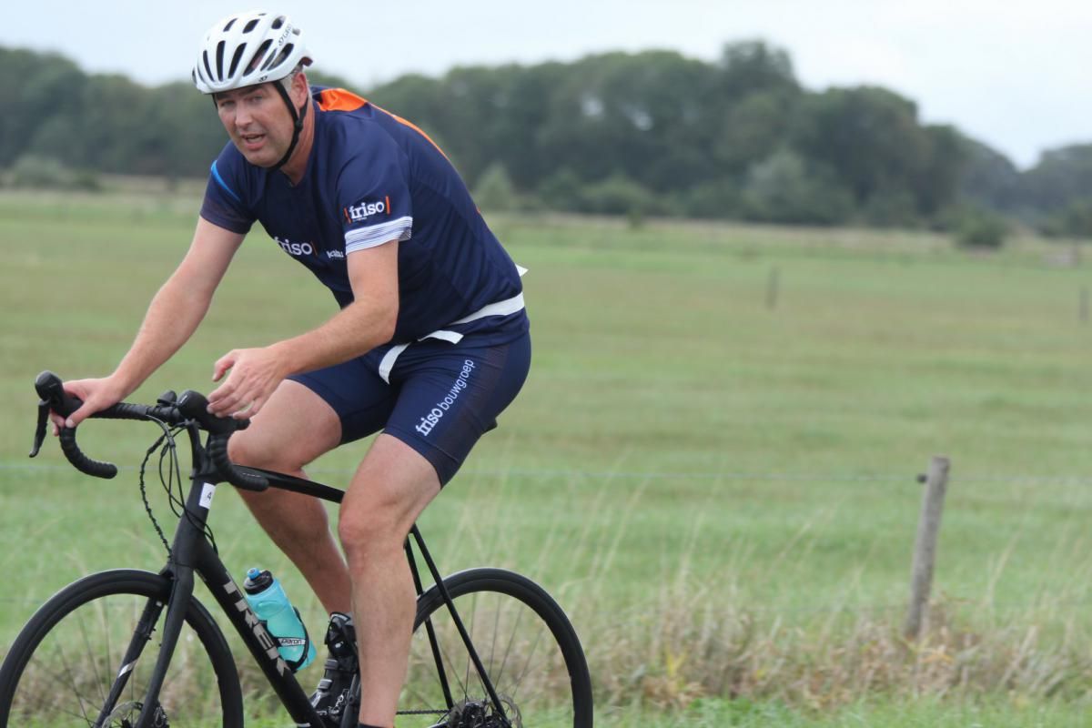 Een man met een helm rijdt op een fiets in een veld