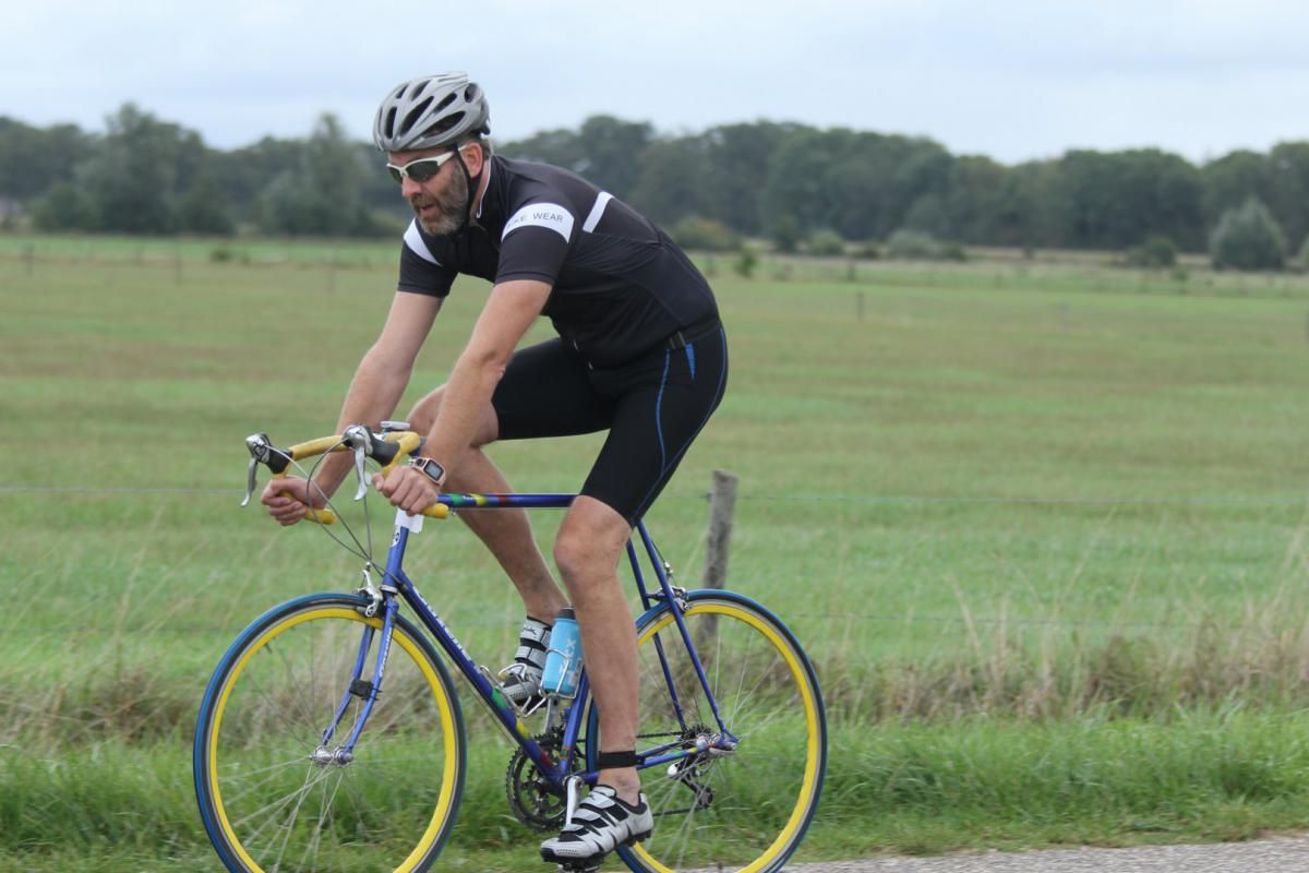 Een man met een helm en een zonnebril fietst op de weg.