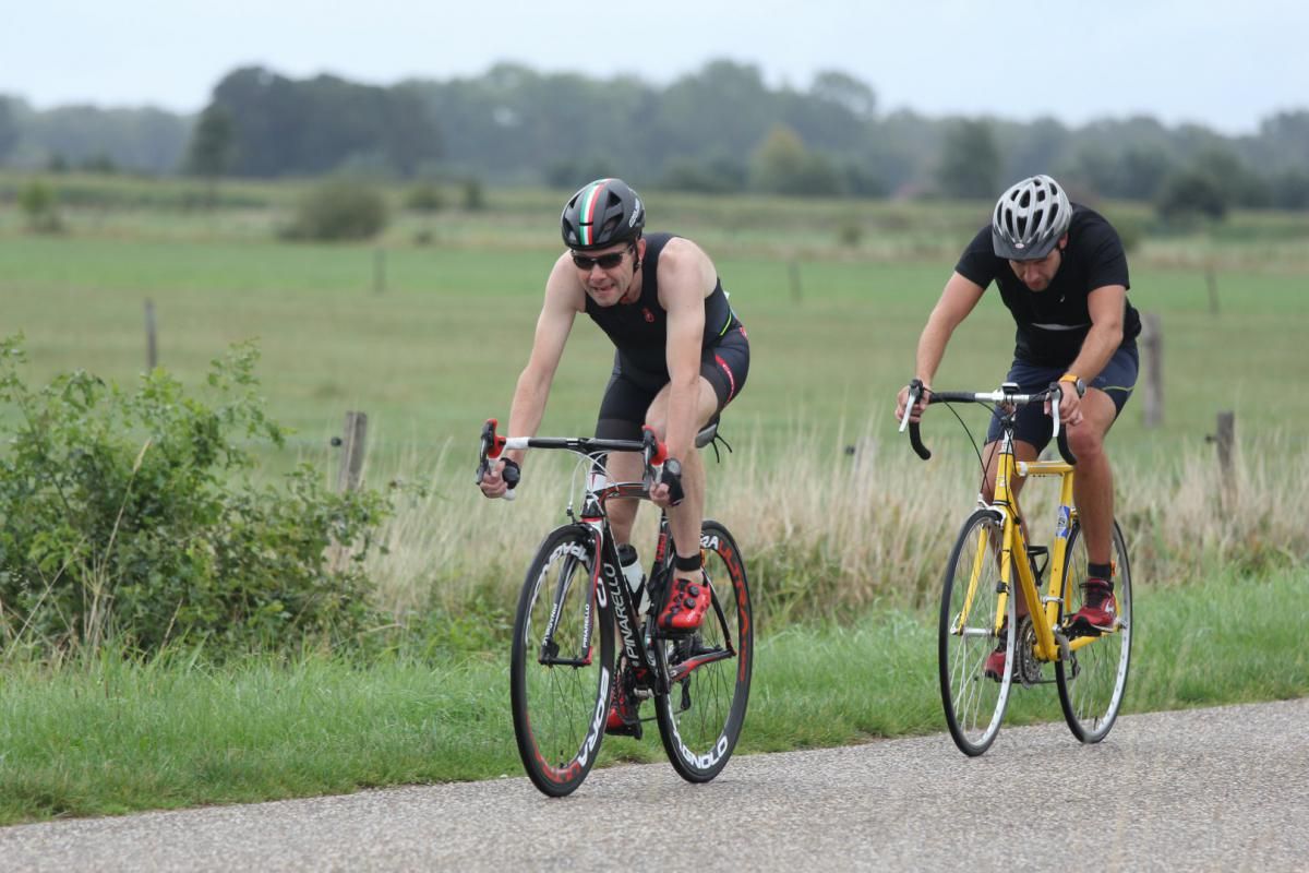 Twee mannen fietsen over een weg.