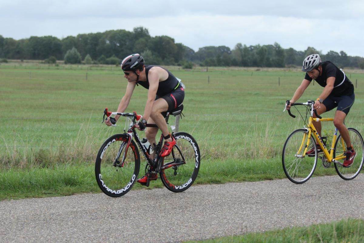 Een man en een vrouw fietsen over een weg.