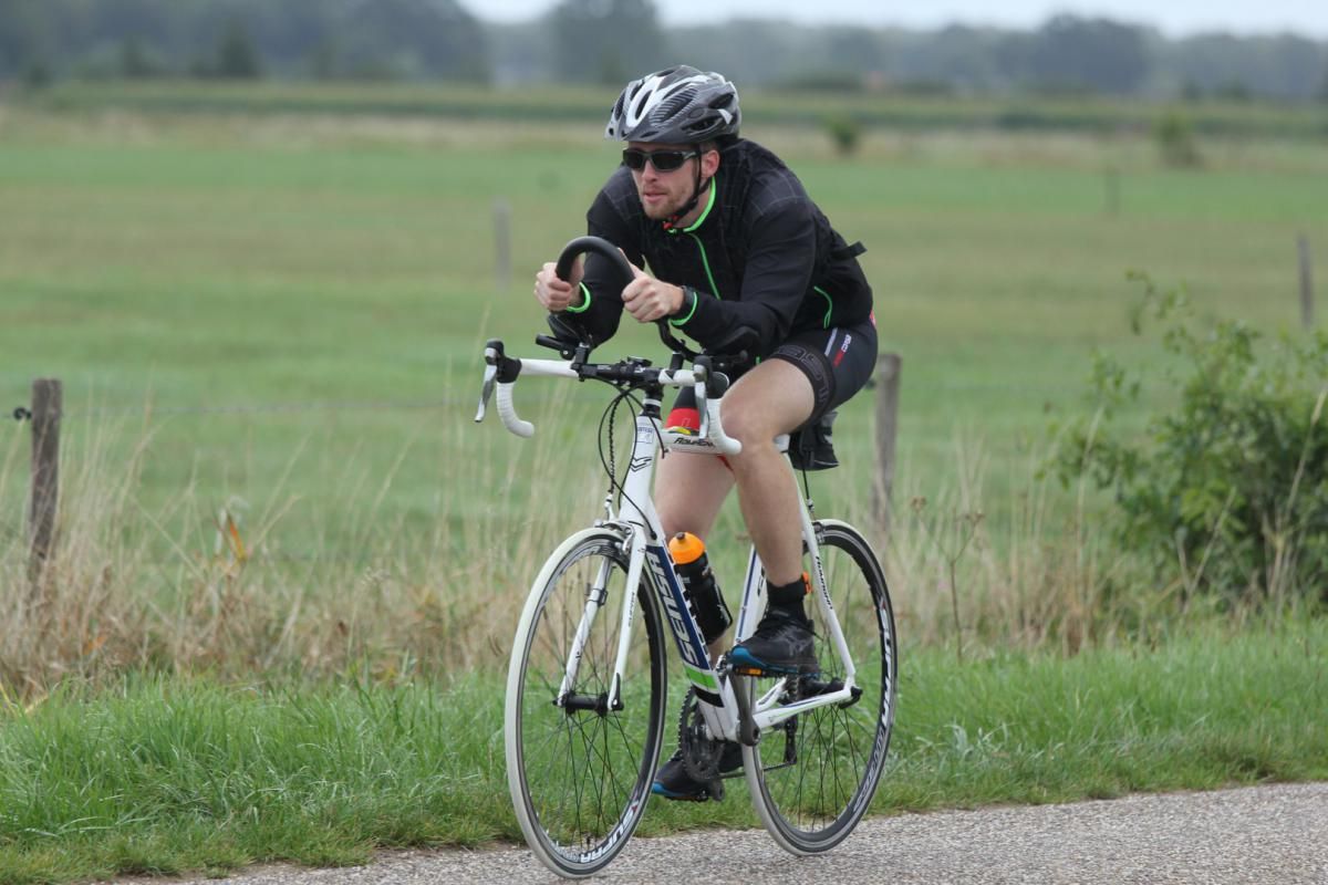 Een man fietst over een onverharde weg.