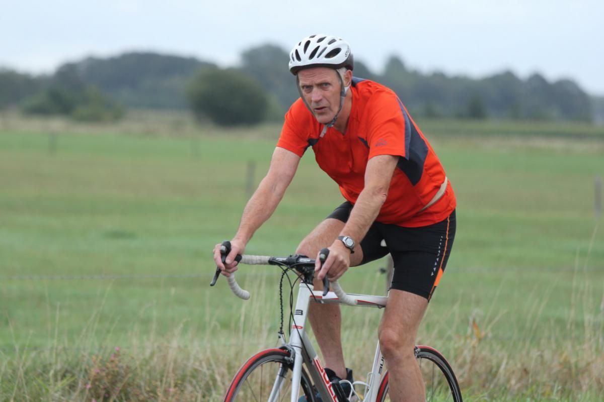 Een man met een helm rijdt op een fiets in een veld.