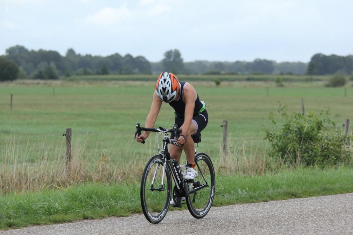 Een man fietst over een weg in een veld.