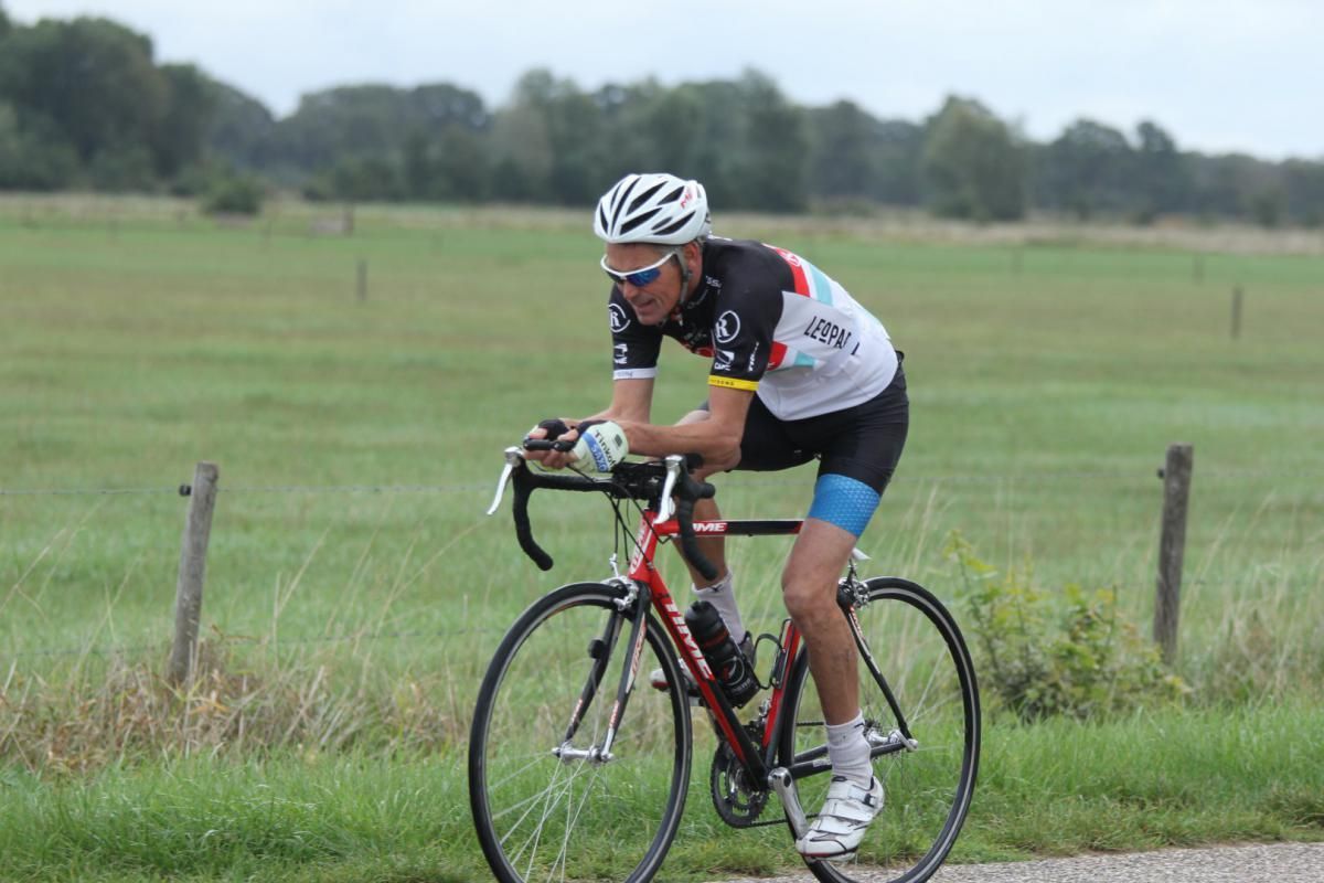 Een man met een helm rijdt op een fiets over de weg.