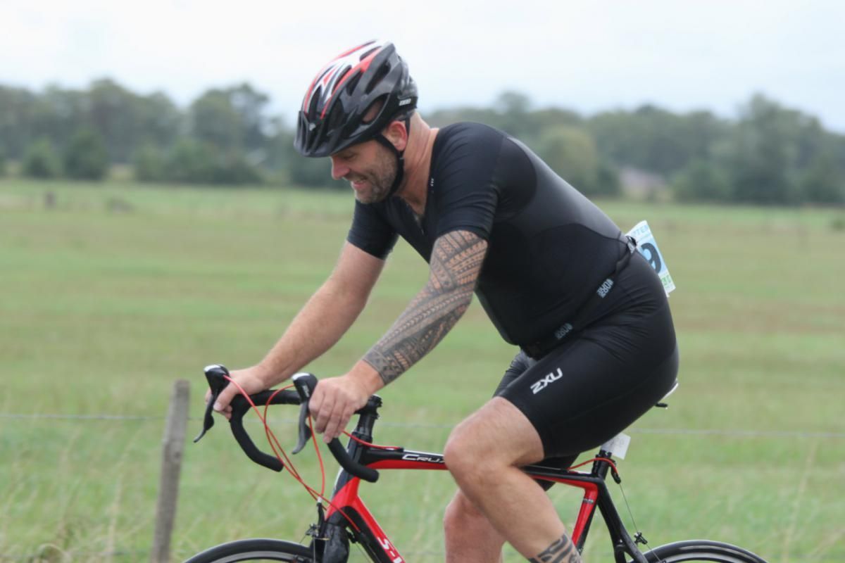 Een man met een helm rijdt op een fiets in een veld