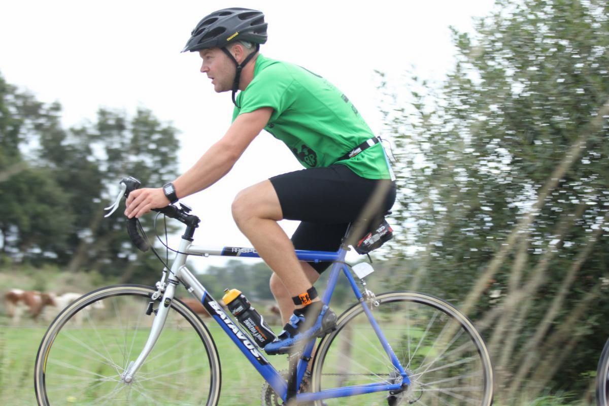 Een man in een groen shirt rijdt op een blauwe fiets