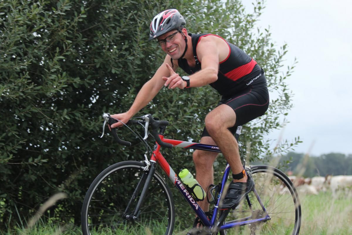 Een man met een helm rijdt op een fiets in een veld