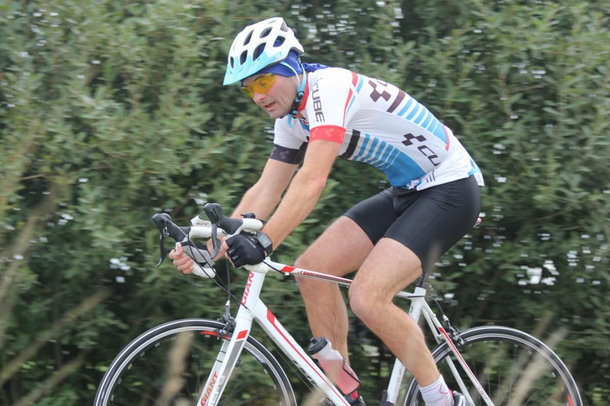 Een man met een helm en een zonnebril rijdt op een fiets
