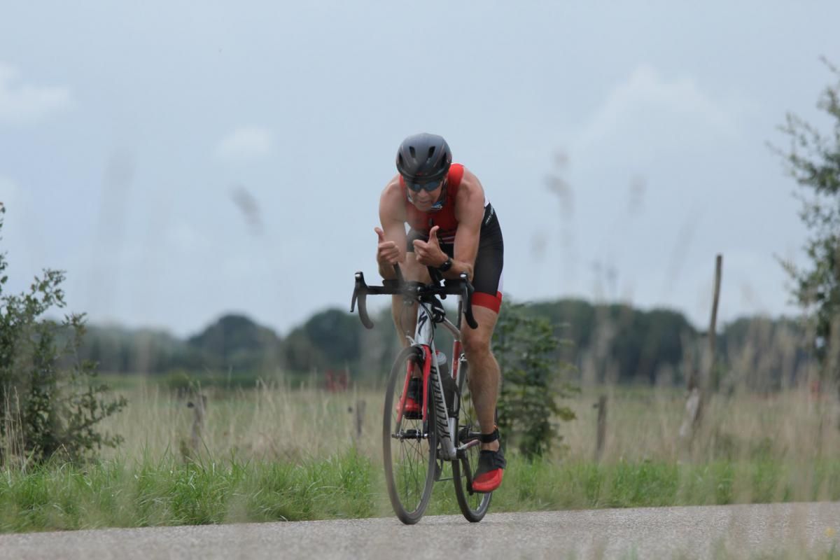 Een man fietst over een onverharde weg.