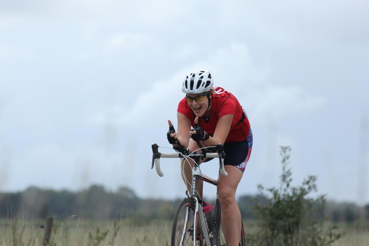 Een vrouw met een helm rijdt op een fiets in een veld.