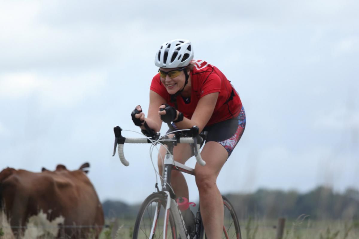 Een vrouw met een helm rijdt op een fiets in een veld.