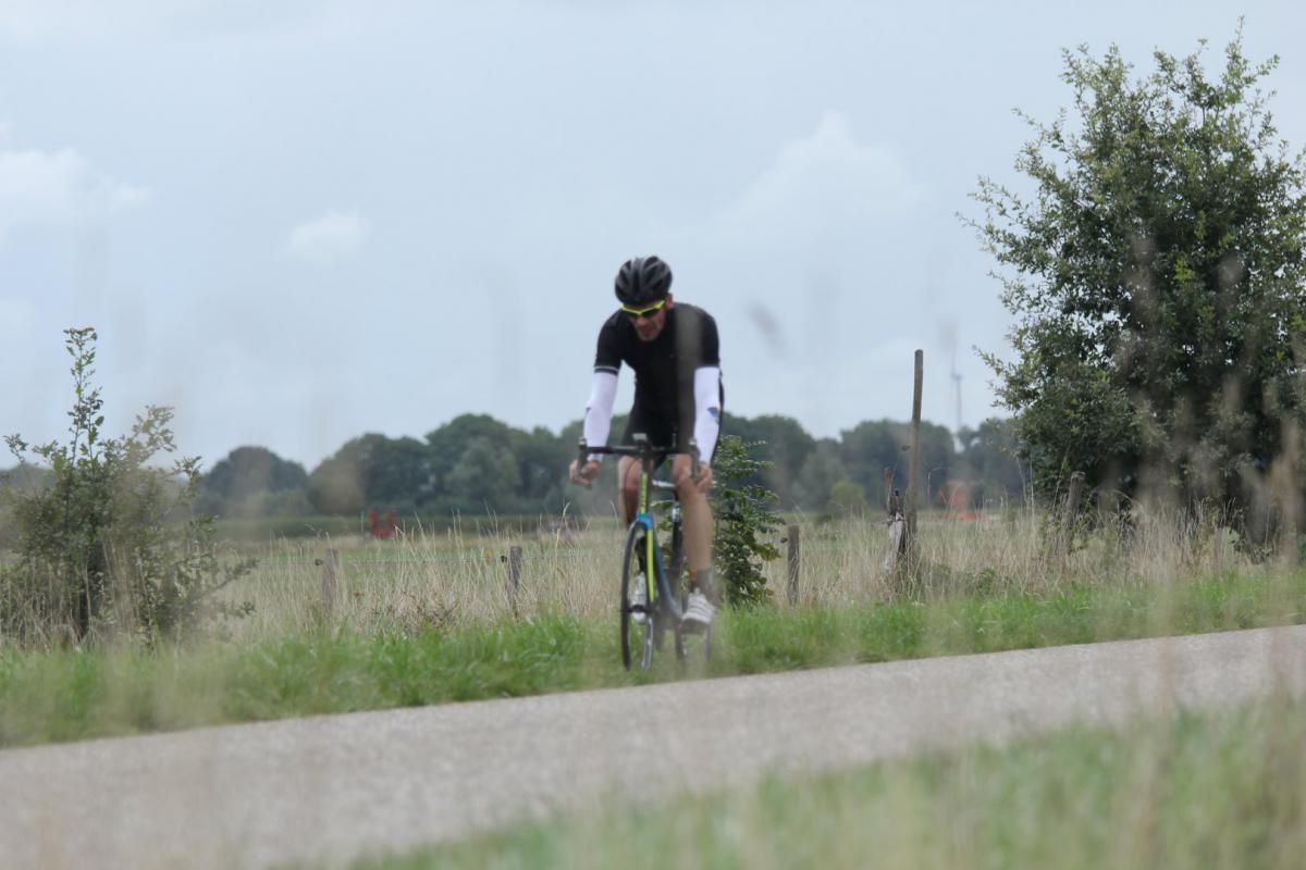 Een man fietst over een onverharde weg.
