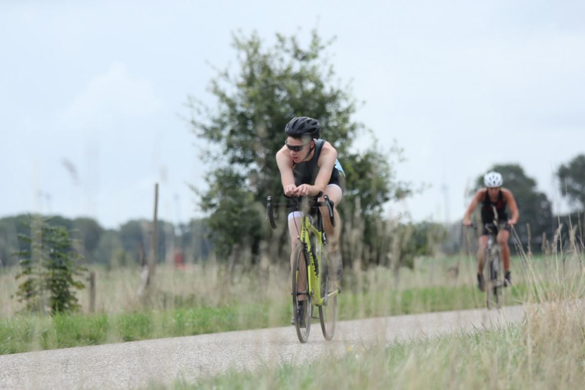 Twee mensen fietsen over een onverharde weg.
