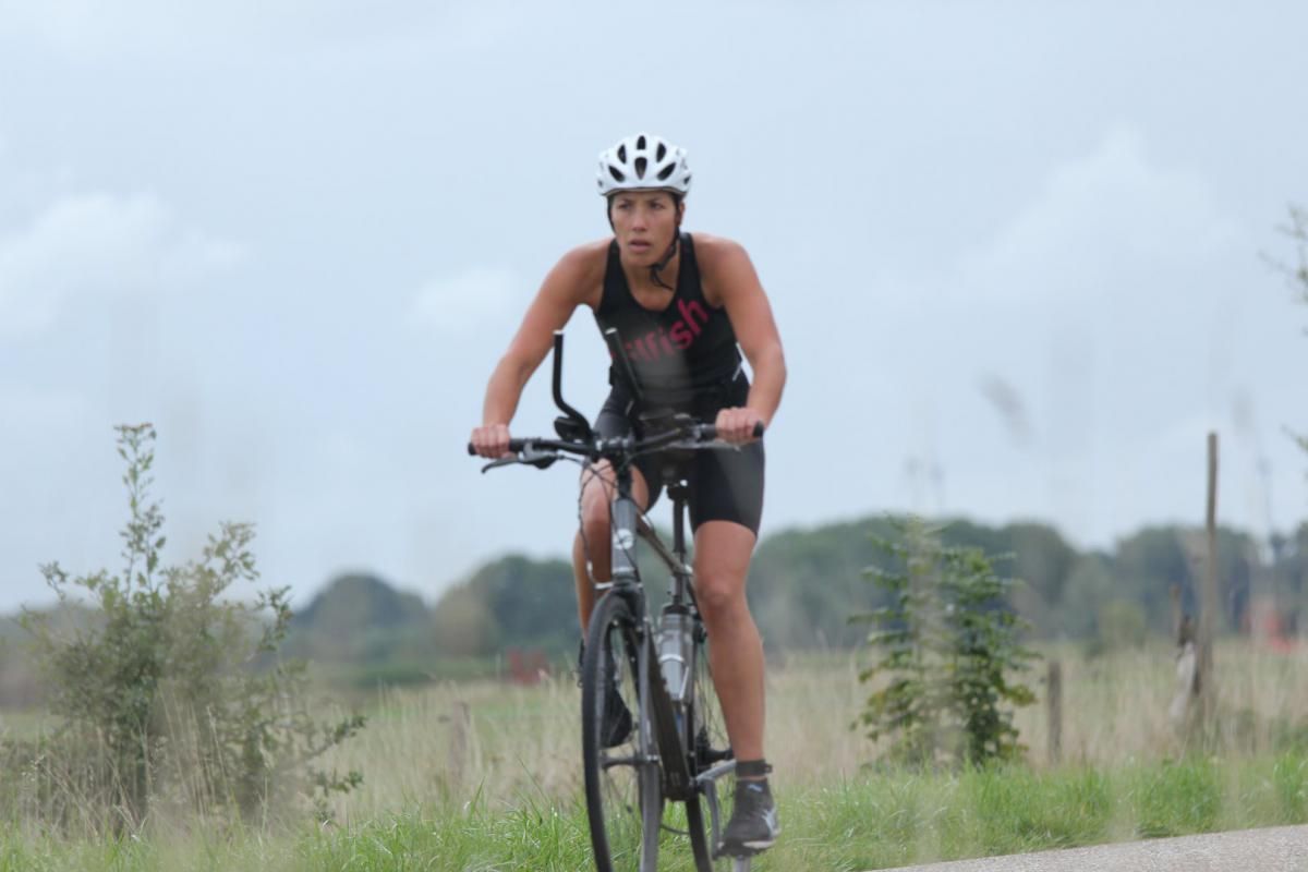 Een vrouw met een helm op fietst over de weg.