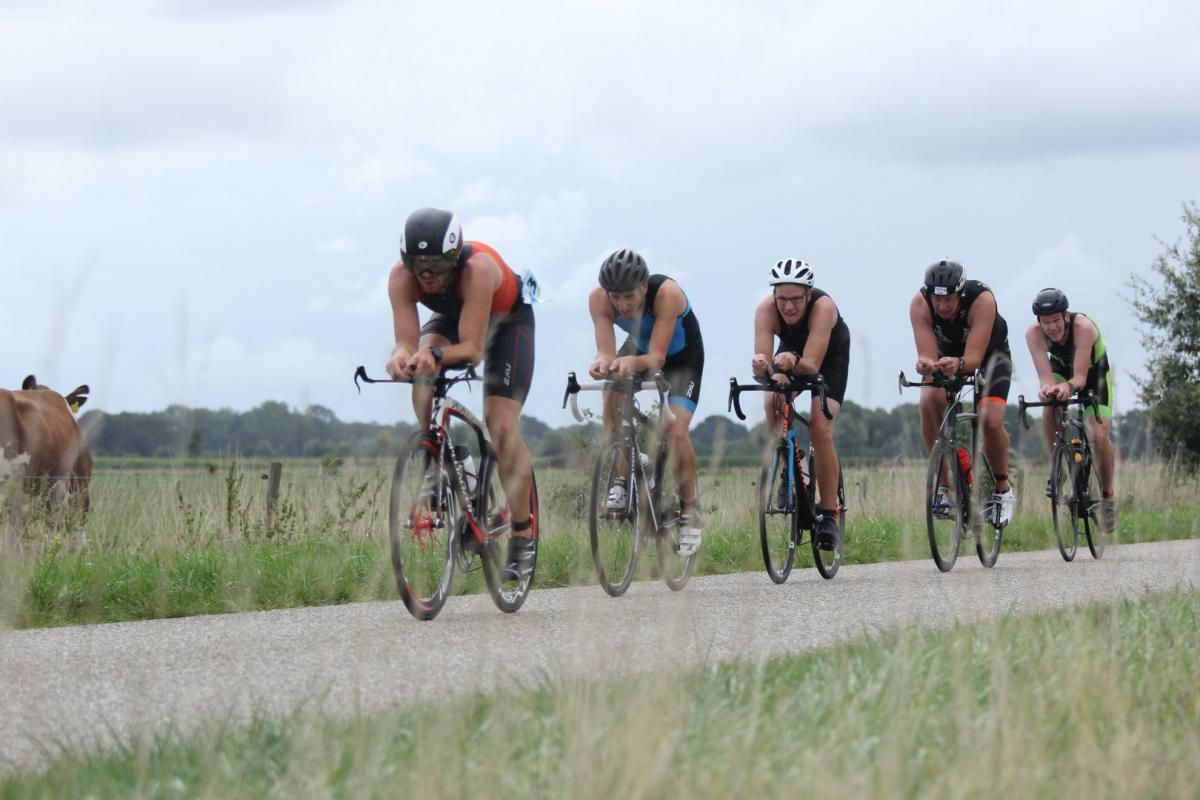 Een groep mensen fietst over een onverharde weg.