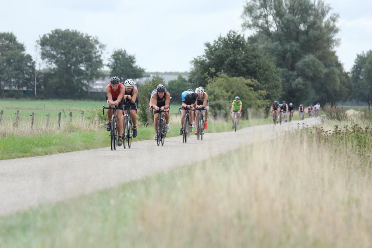 Een groep mensen fietst over een onverharde weg.
