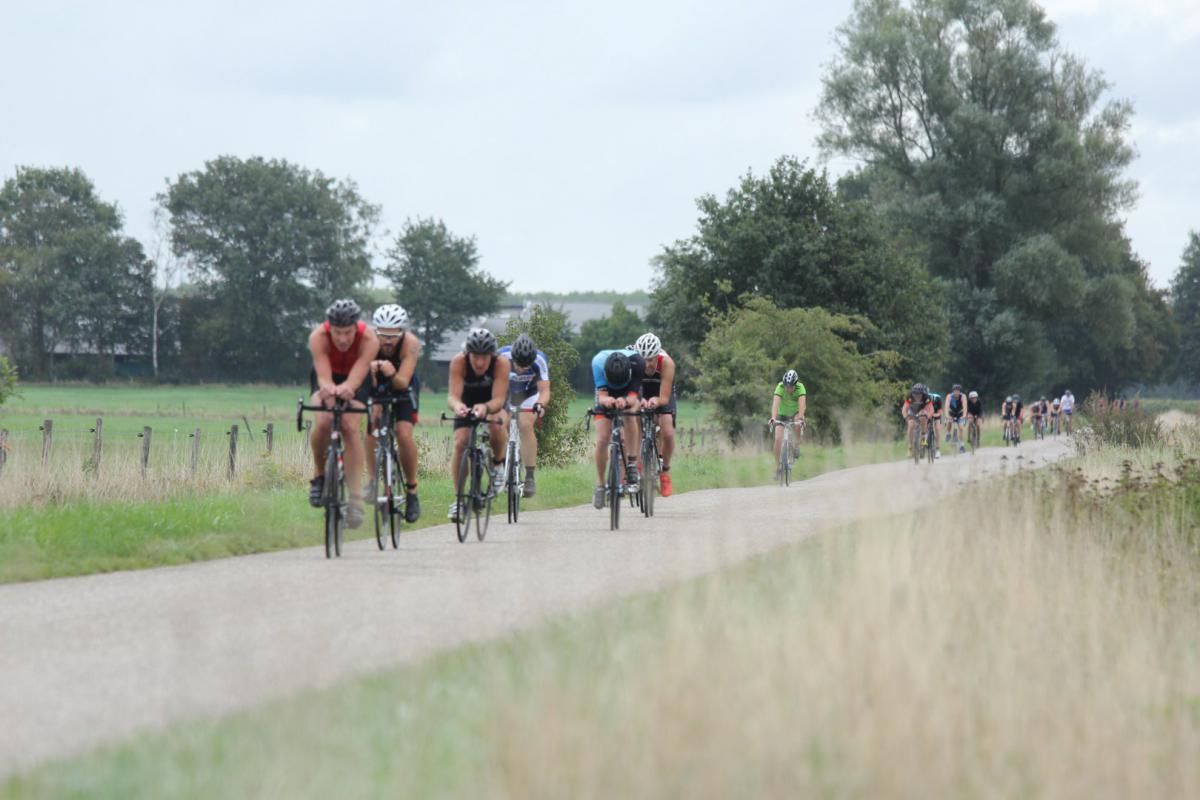 Een groep mensen fietst over een onverharde weg.