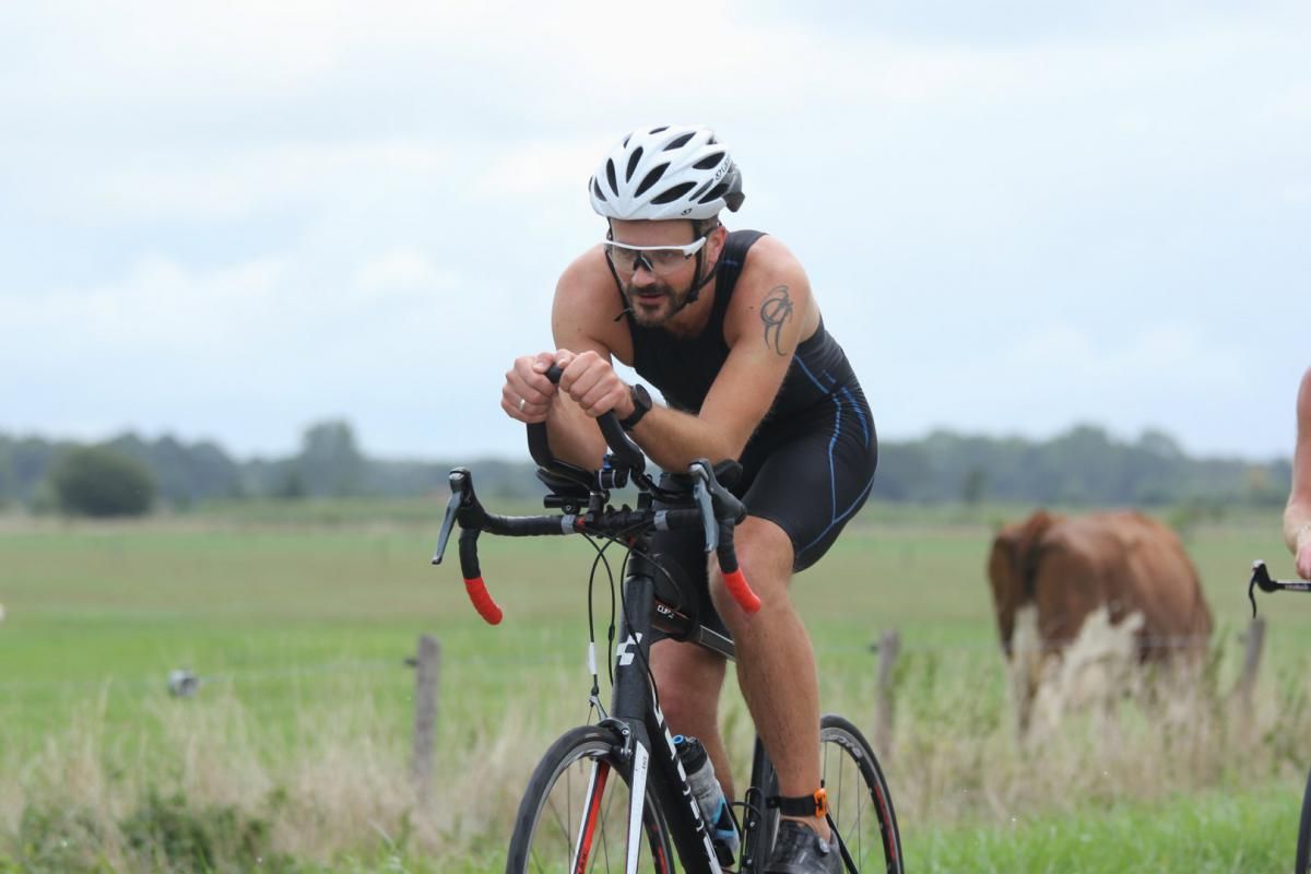 Een man met een helm rijdt op een fiets in een veld.