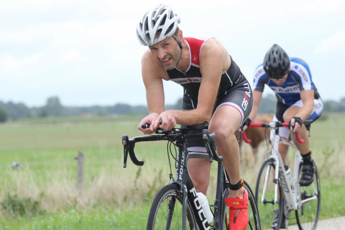 Twee mannen fietsen op een weg in een veld.