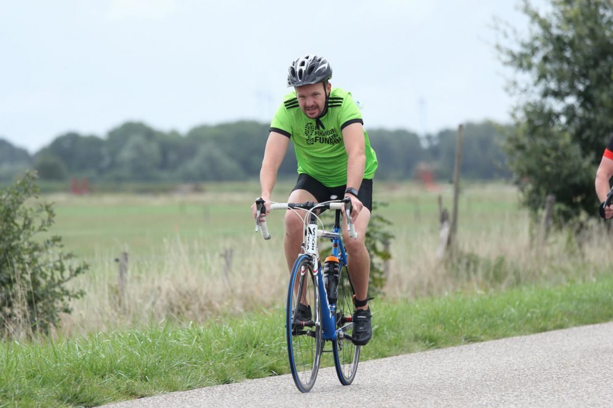 Een man in een groen shirt fietst over de weg.