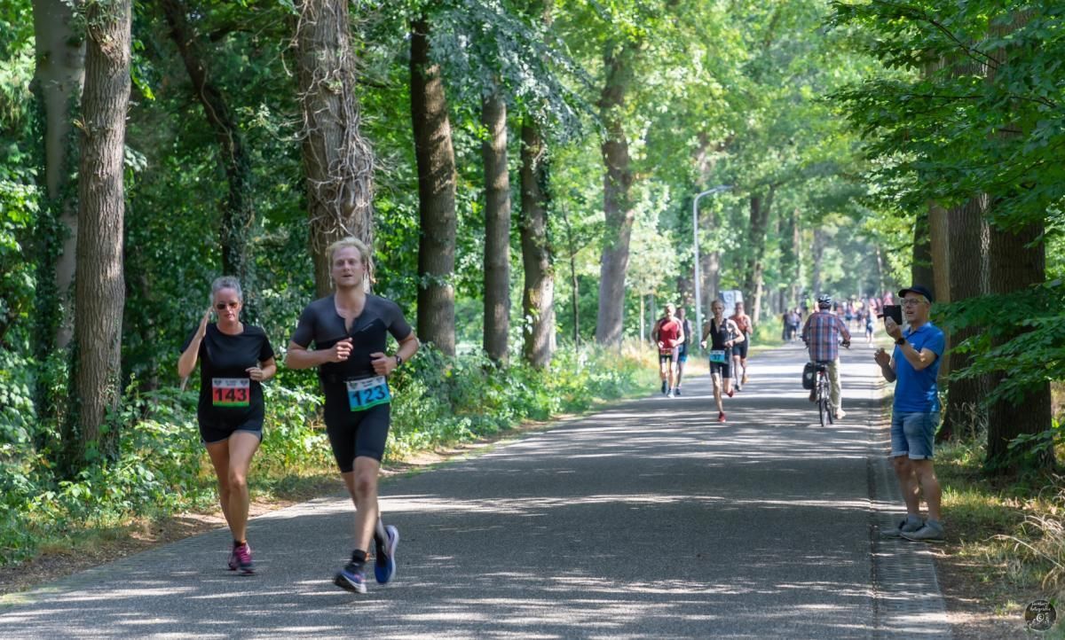 Triathlon Eibergen. Een groep mensen rent over een pad in het bos.