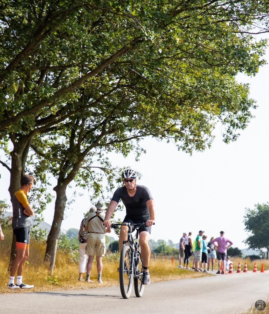 Een man fietst over een weg terwijl mensen kijken