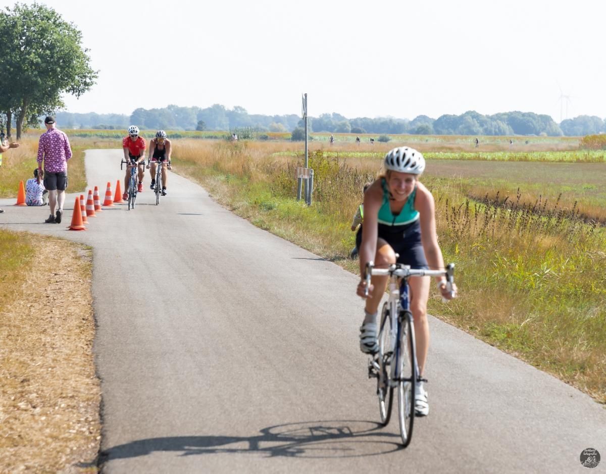 Een vrouw met een helm rijdt op een fiets over een weg