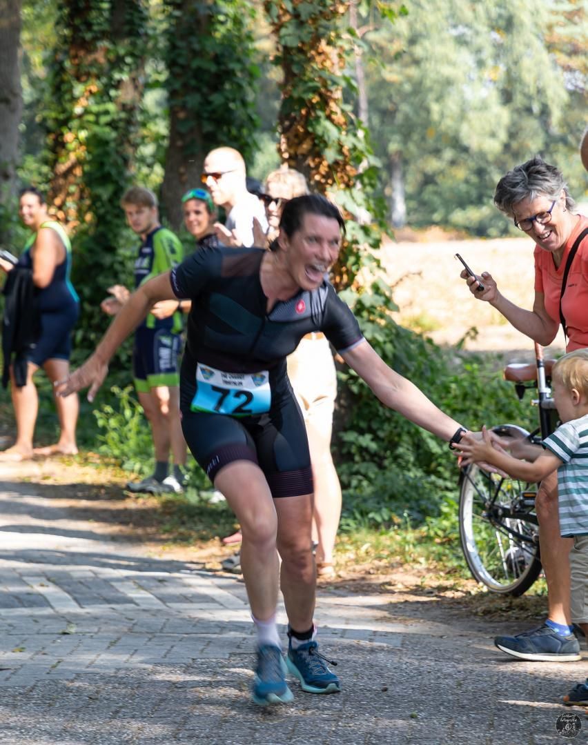 Een vrouw houdt de hand van een kind vast tijdens een hardloopwedstrijd.