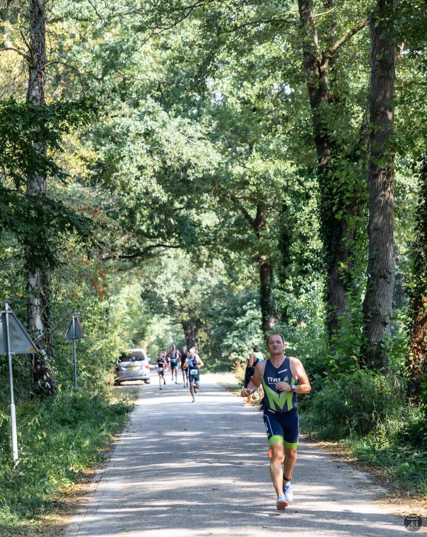 Een man rent over een onverharde weg in het bos.
