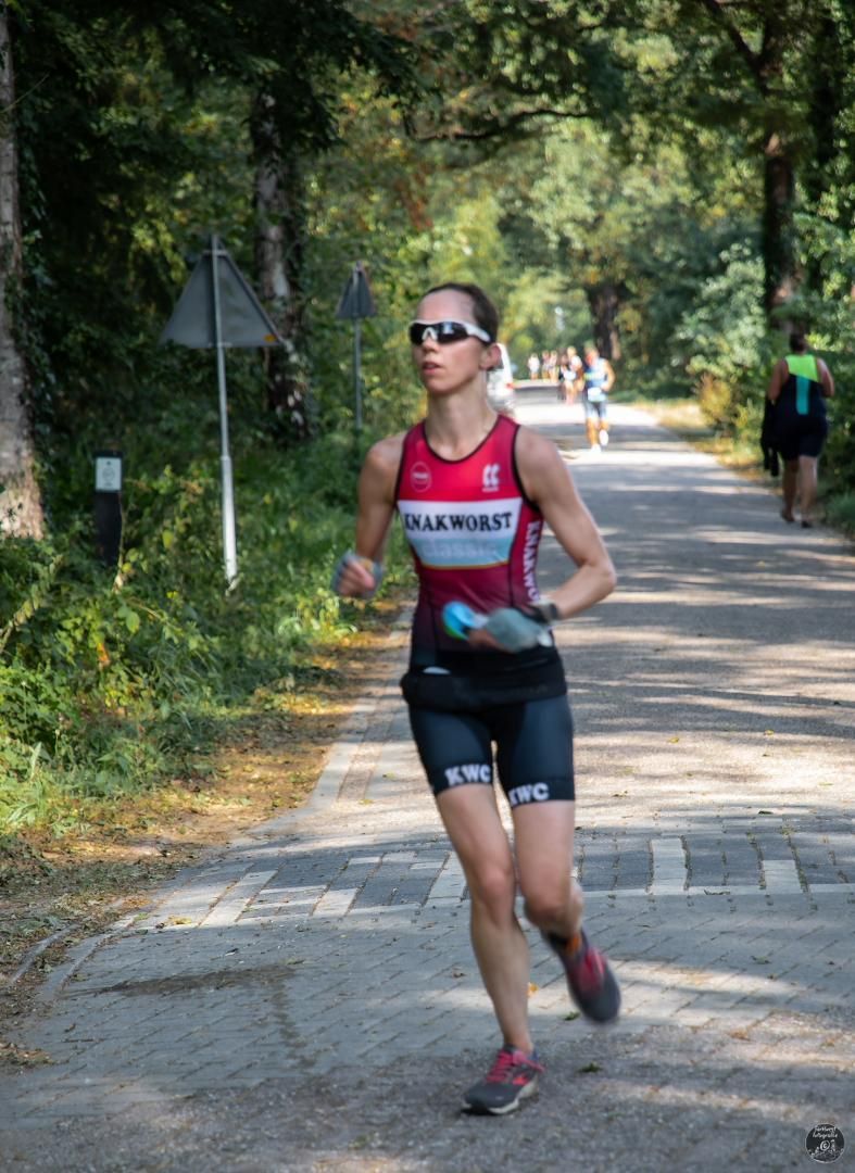 Een vrouw rent over de weg met een zonnebril op.