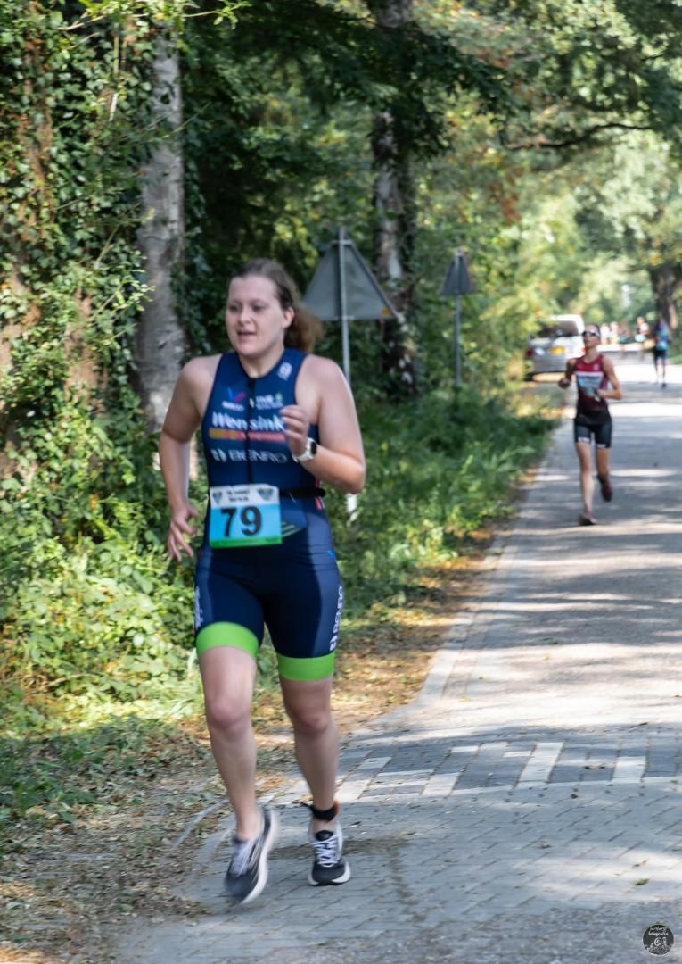 Een vrouw rent over de weg met het nummer 79 op haar shirt.