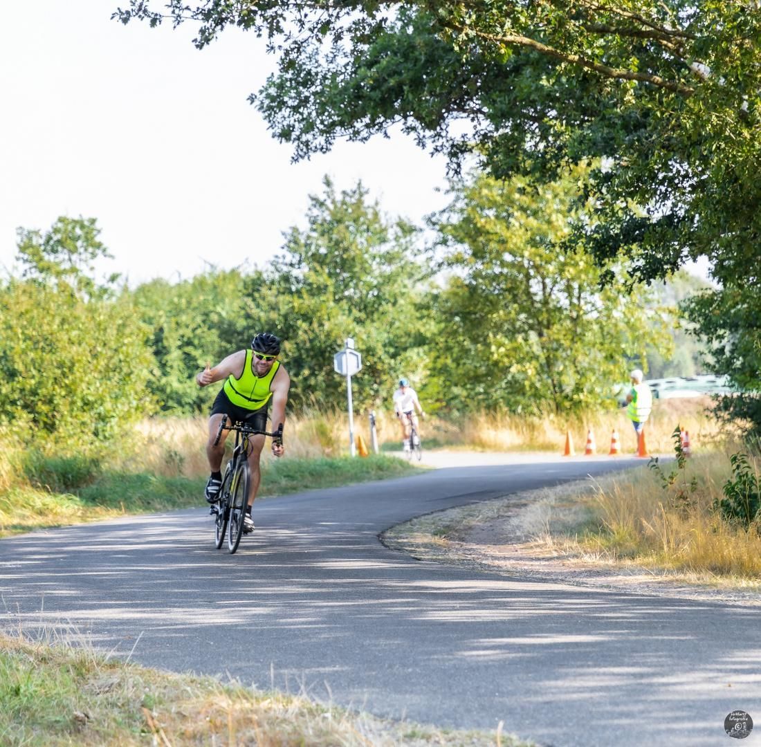 Een man in een geel shirt fietst over een weg