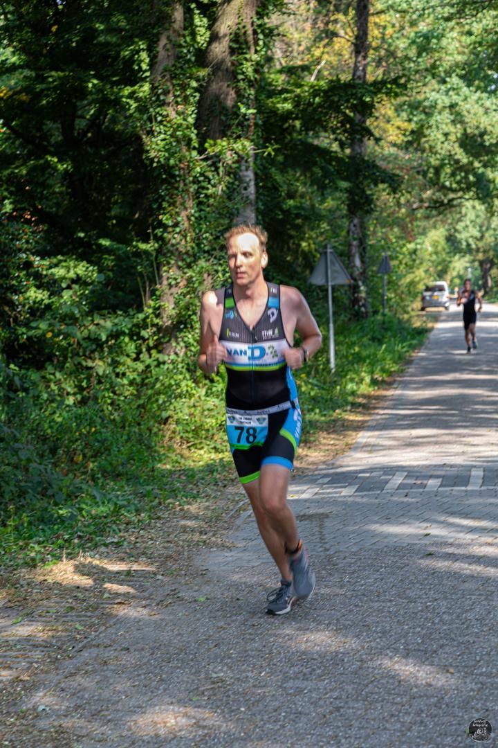 Een vrouw rent over een weg in het bos.