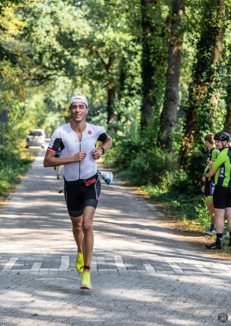 Een man rent over een weg in het bos.