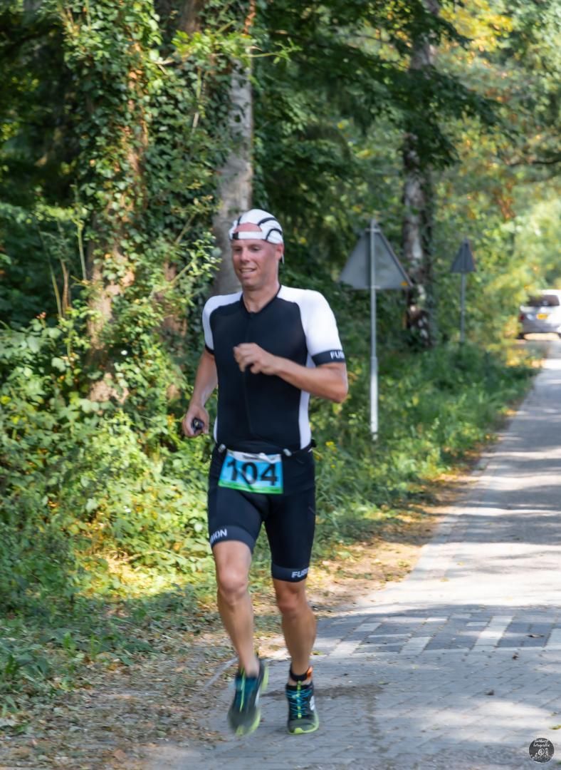 Een man rent over een weg in het bos.