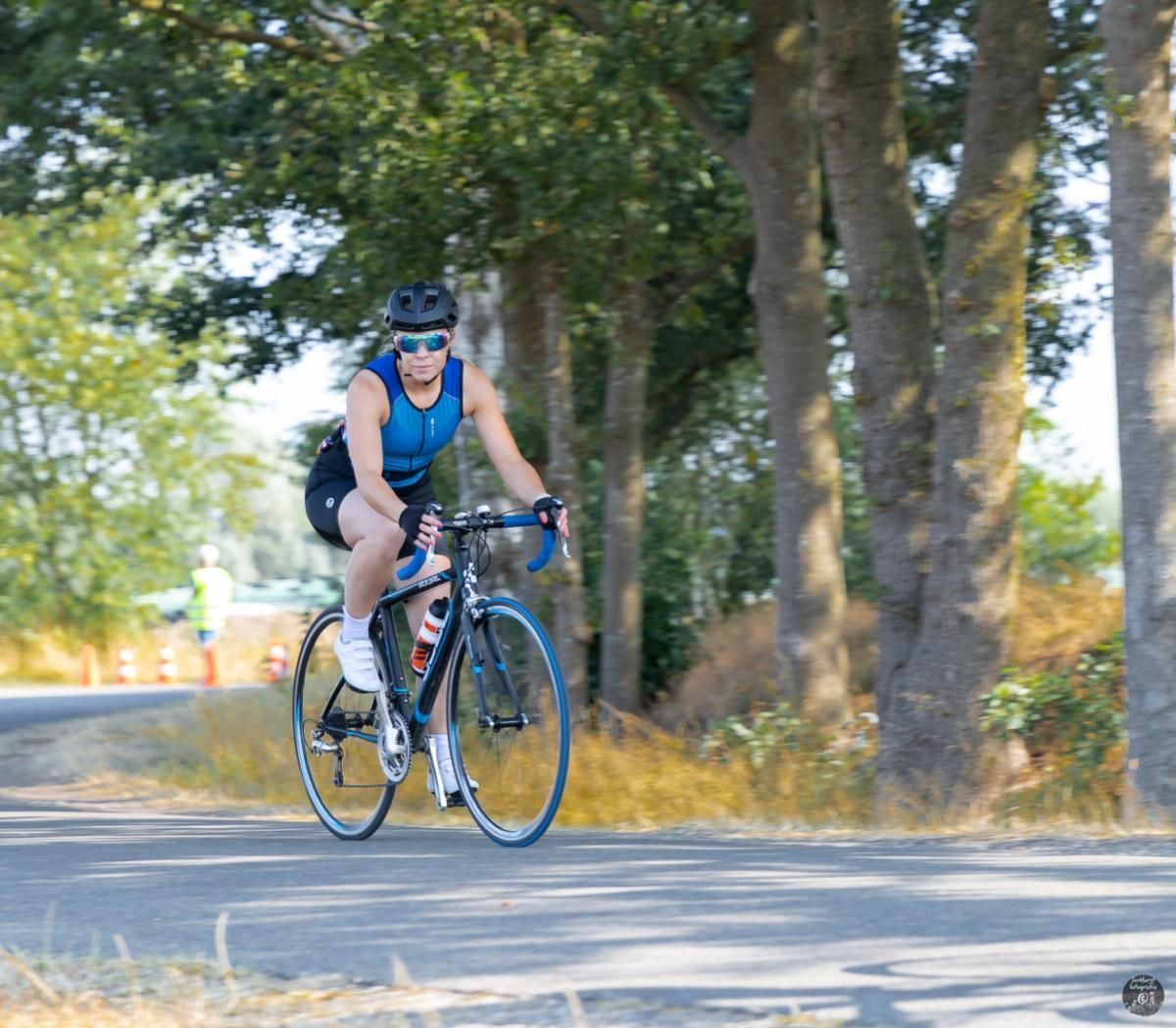 Een persoon fietst over een weg met bomen op de achtergrond