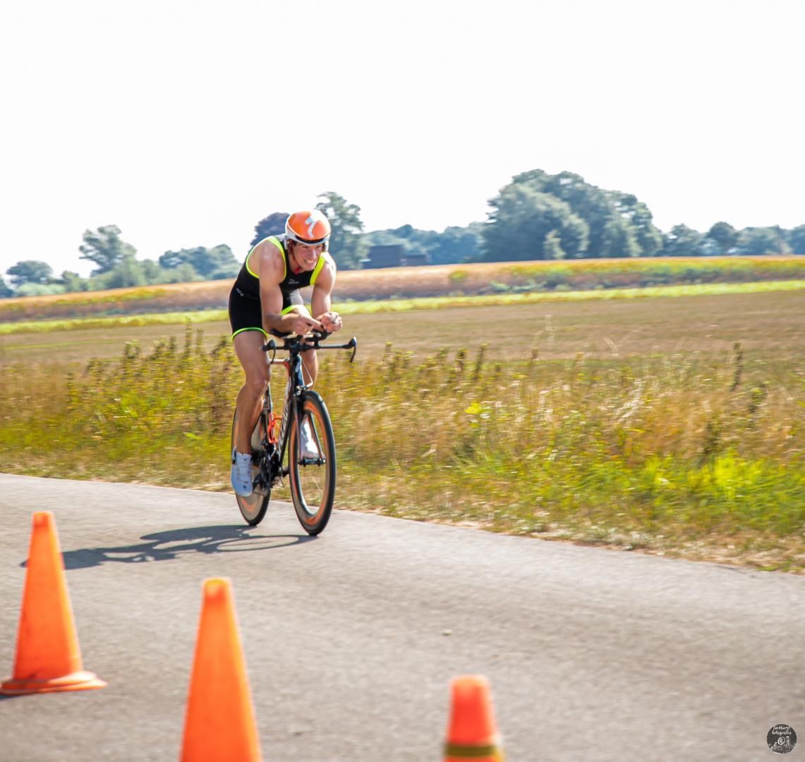 Een man fietst over een weg naast oranje kegels.