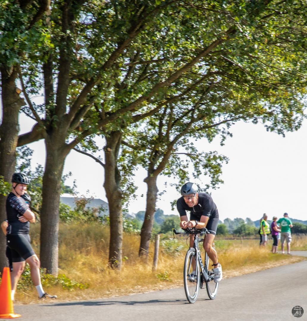 Een man fietst over een weg met bomen op de achtergrond
