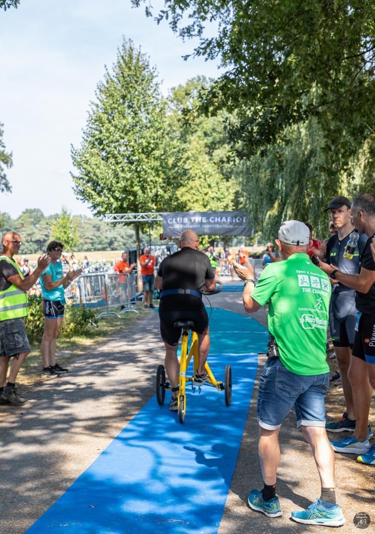 Een groep mensen staat rond een man die op een fiets rijdt.