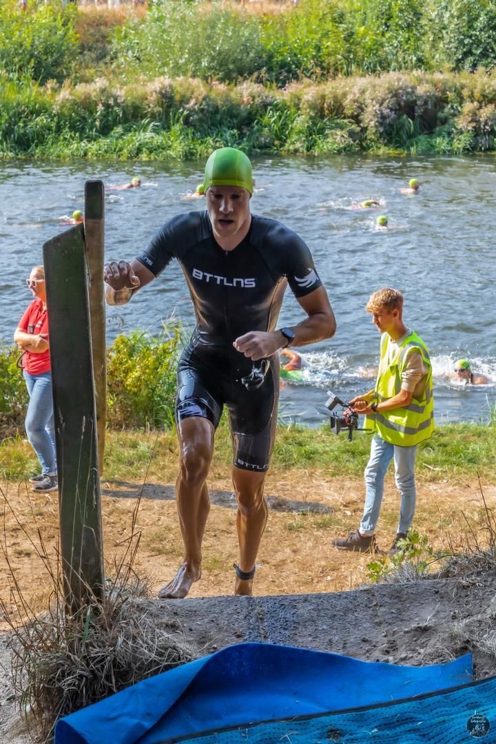 Een man in een wetsuit rent het water in.
