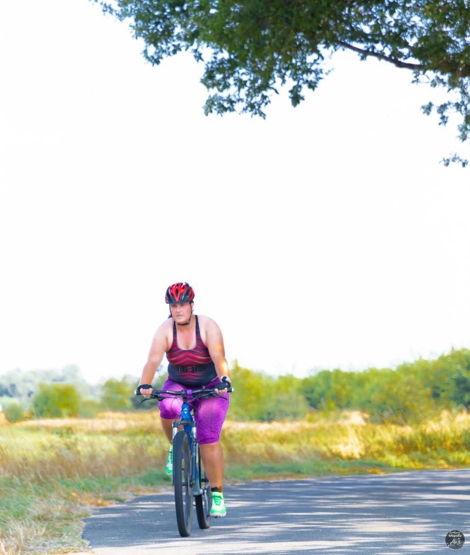 Een vrouw met een helm rijdt op een fiets over een weg