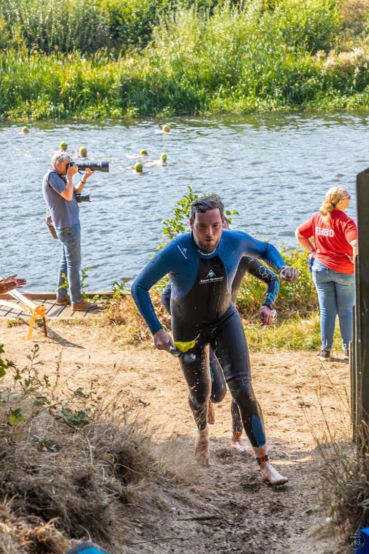 Een man in een wetsuit rent naar een watermassa.