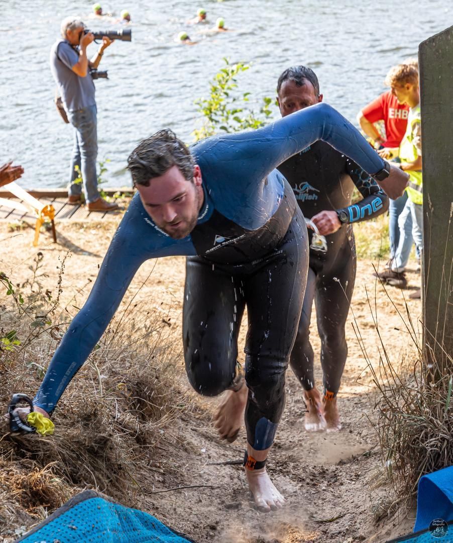 Een man in een wetsuit springt in het water.