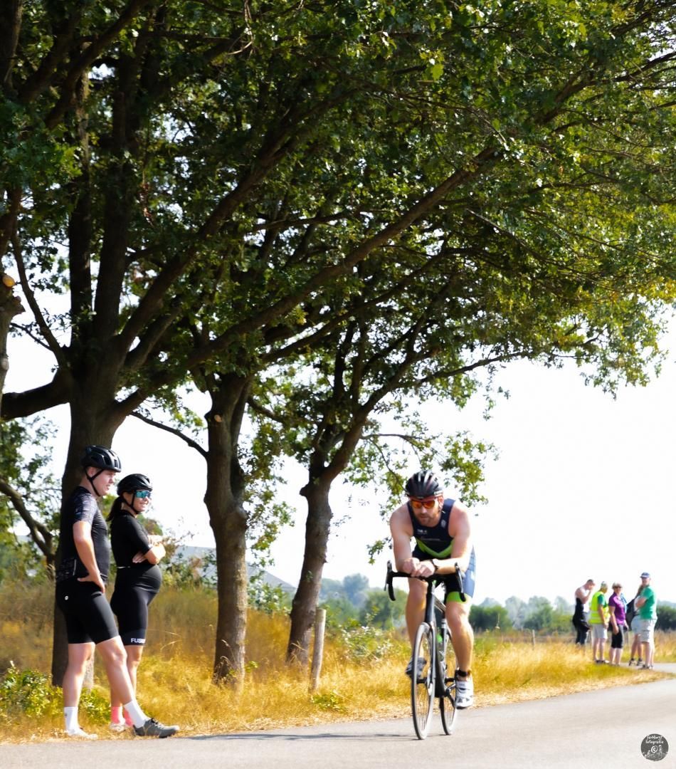 Een man fietst over een weg met bomen op de achtergrond