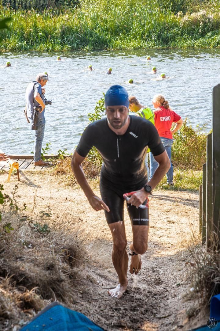 Een man in een wetsuit rent naar een watermassa.