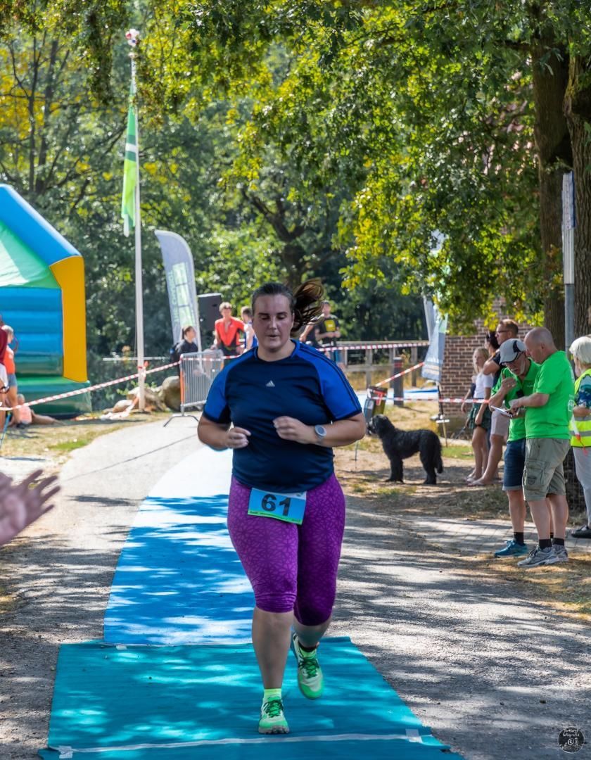 Een vrouw in een paarse korte broek rent over een blauwe loper.