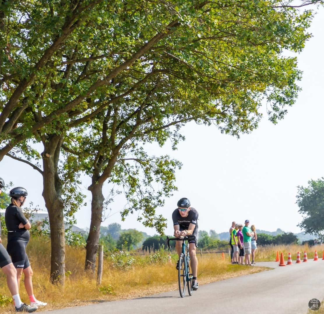 Een man fietst over een weg terwijl mensen kijken