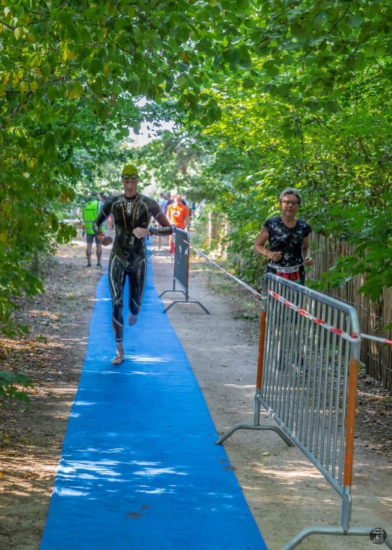 Een man in een wetsuit rent over een blauwe loper.
