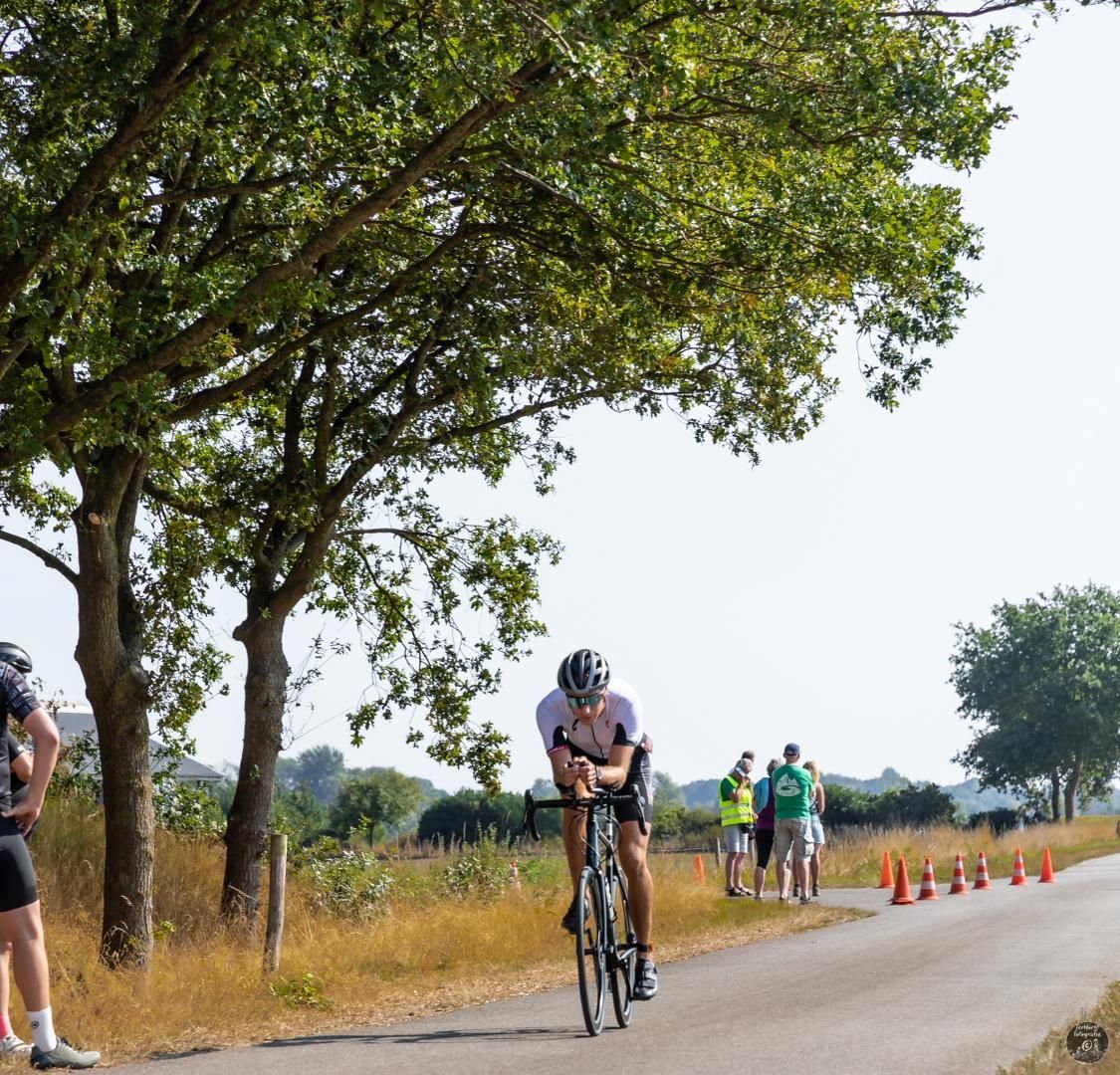 Een man met een helm rijdt op een fiets over een weg