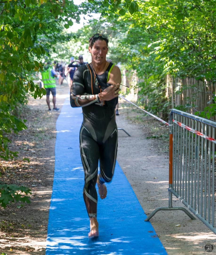 Een man in een wetsuit rent op een blauwe mat